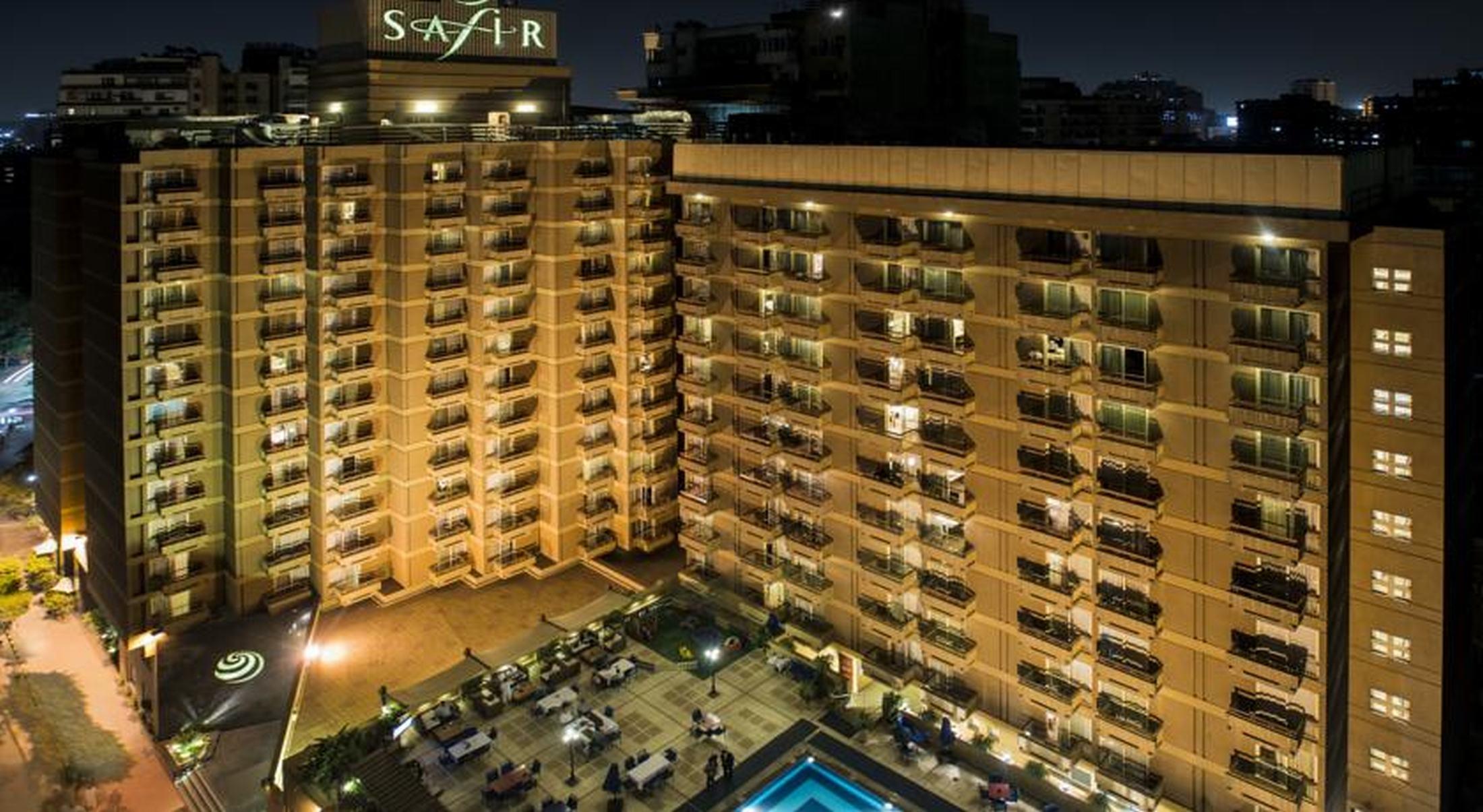 Safir Hotel Cairo Giza Exterior foto The photo shows a multi-story hotel building at night. The building is illuminated, showcasing multiple balconies along its facade. In front of the hotel, there is an outdoor area with seating arranged around a pool, which is also lit up. The hotel's