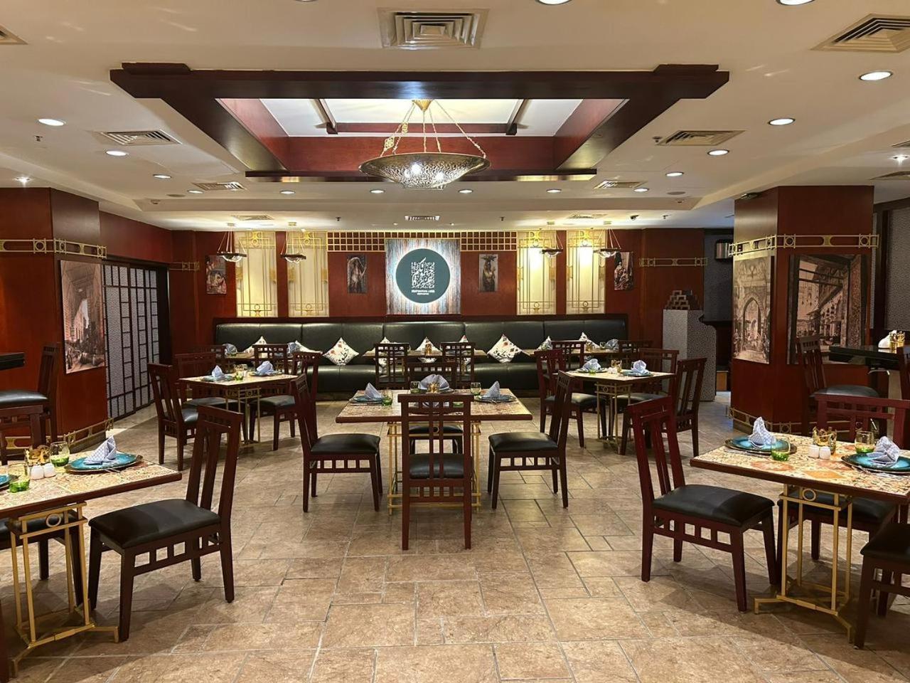 Safir Hotel Cairo Giza Exterior foto The photo shows the interior of a restaurant. The space features a combination of warm wood tones and elegant decorations. There are several dining tables arranged throughout, each set with plates, cutlery, and decorative napkins. The walls are adorn