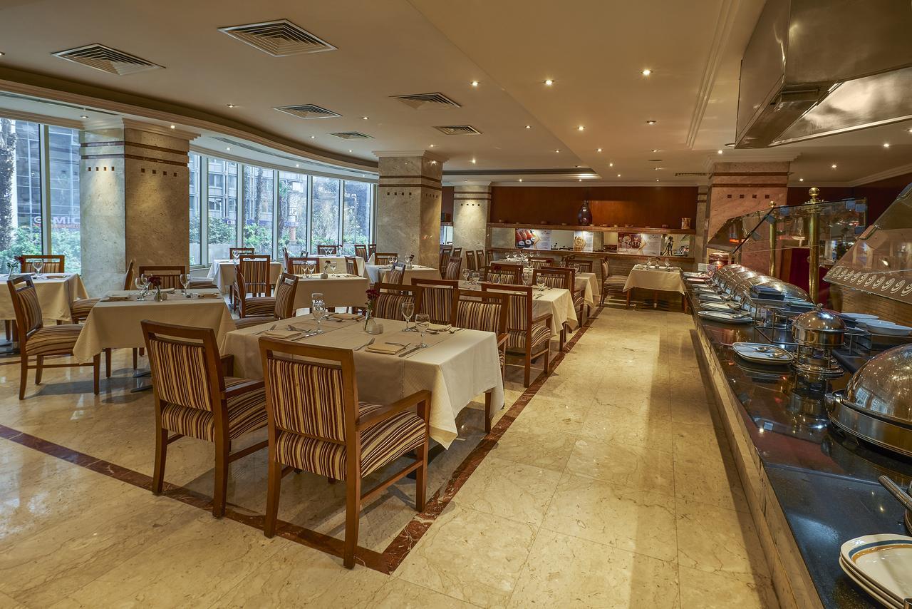 Safir Hotel Cairo Giza Exterior foto The photo shows the interior of a restaurant. It features a spacious dining area with several tables laid out with white tablecloths. The tables are accompanied by wooden chairs that have striped patterns. The restaurant is well-lit with soft lightin